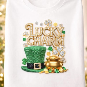 Peut inclure: T-shirt blanc avec un motif de la Saint-Patrick. Le graphisme comprend les mots "Lucky Charm" en lettres dorées et diamantées, un chapeau de lutin vert, un pot d'or et des trèfles.