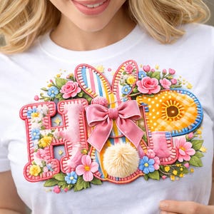 Peut inclure: T-shirt blanc avec un motif coloré "HIP" représentant un lapin, des fleurs et un nœud. Le motif comprend les lettres "H", "I" et "P" avec des détails floraux et à motifs, et une queue touffue.