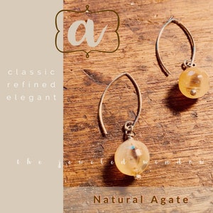 May include: A pair of silver earrings with natural agate stones. The stones are a light brown color with a translucent quality. The earrings are simple and elegant.