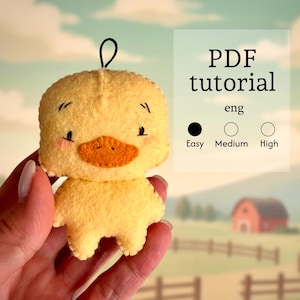 May include: A handmade yellow felt duck ornament with an orange beak and black eyes. The duck has a loop for hanging and is held in a hand. Text on the image reads "PDF tutorial eng" with difficulty levels: Easy, Medium, and High.