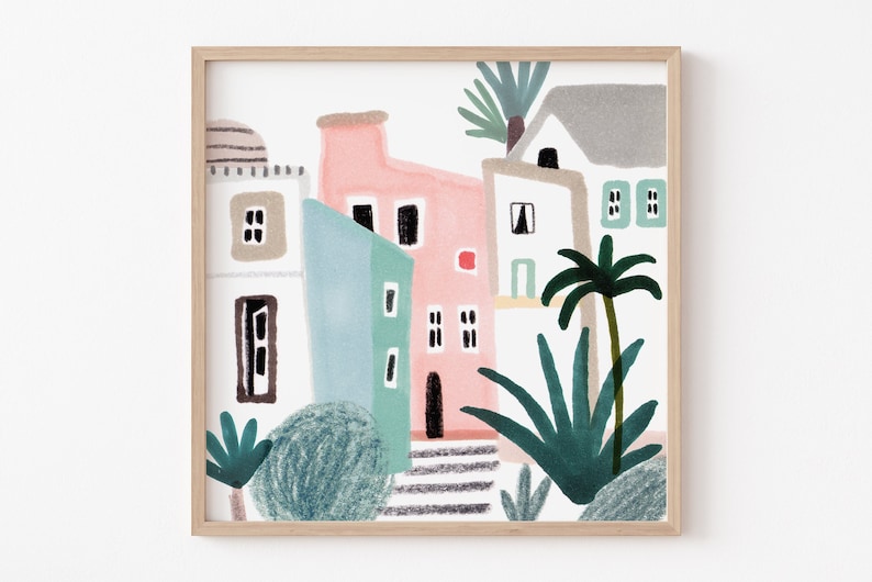 Op de afbeelding: Een ingelijste kunstdruk met een kleurrijke illustratie van gebouwen in roze, blauw en wit. Palmbomen en andere groenvoorzieningen zijn ook afgebeeld. Het kunstwerk heeft een grillige, handgetekende stijl, perfect om een vleugje kustcharme toe te voegen.