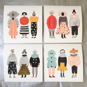 May include: Four square art prints featuring whimsical illustrations of figures in colorful outfits. Each figure has a unique design, with varying patterns, shapes, and color palettes, including stripes, polka dots, and geometric forms. The prints are on a white background.