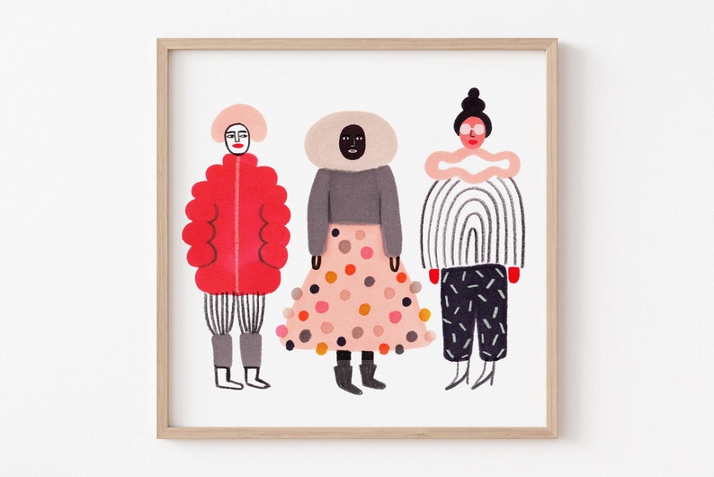 May include: A framed art print featuring three stylized figures in colorful outfits. The figures are depicted in a whimsical style, with bold colors and patterns. The artwork is set against a white background, and framed in a light wood frame.