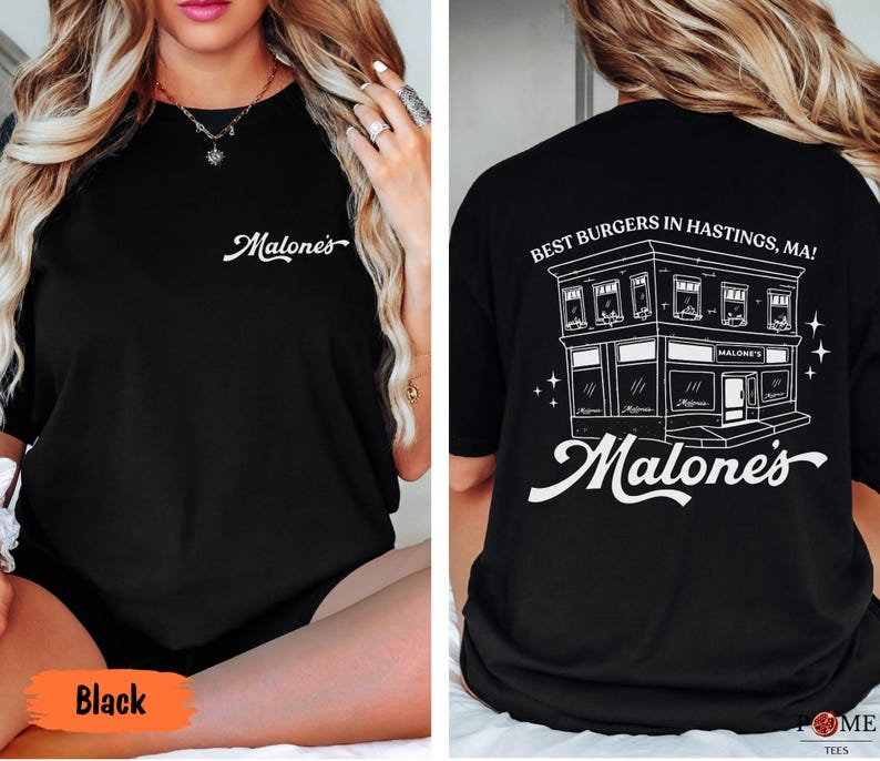 May include: A black t-shirt featuring the white text Malone's on the front chest. The back displays a white line drawing of a building with the text Best Burgers in Hastings, MA! and the word Malone's in a large script font below the building.