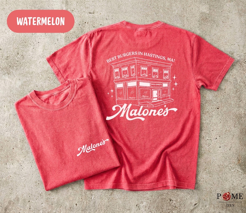 May include: A watermelon red short-sleeve t-shirt featuring a white graphic on the back of a building with the text BEST BURGERS IN HASTINGS, MA! and Malone's. The front left chest area displays the white text Malone's in a cursive script font.