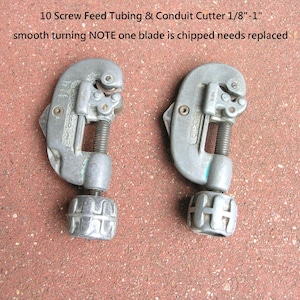 Puede incluir: Dos cortadores de tubos y conductos de alimentaci&oacute;n por tornillo de color plateado. El texto de la imagen dice: "10 Screw Feed Tubing & Conduit Cutter 1/8"-1" smooth turning NOTE one blade is chipped needs replaced."