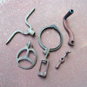May include: An assortment of vintage metal hardware pieces, including a circular clamp, a curved handle, and a three-pronged tool. The items are in various shades of gray and brown, with signs of wear and age.