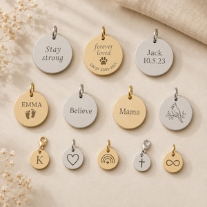 Puede incluir: Una colección de dijes metálicos circulares en tonos oro y plata, con varios grabados que incluyen los textos Stay strong, forever loved con una huella, Jack 10.5.23, EMMA con huellas de pies, Believe, Mama, un cardenal, K, un corazón, un arcoíris, una cruz y un símbolo de infinito.