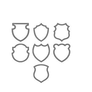 May include: A collection of seven distinct shield-shaped outlines arranged in a cluster. Each shield features a unique contour, rendered in simple black lines against a plain white background, showcasing various heraldic and geometric border styles.