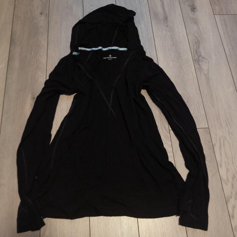 May include: Black hooded long-sleeve shirt. The shirt has a V-neck design and a hood. The hood has a light blue and white trim. The shirt is made of a soft, lightweight material. The shirt has a small logo on the chest.