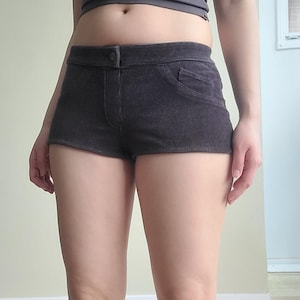 Puede incluir: Pantalones cortos de pana gris oscuro con cierre de botón y un pequeño bolsillo en el lado derecho. Los pantalones cortos tienen un diseño clásico y una apariencia texturizada. Colección de ropa casual.