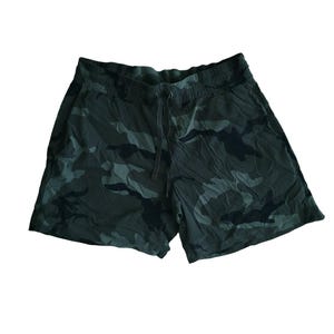 Puede incluir: Unos pantalones cortos deportivos con un patrón de camuflaje en verde oscuro y negro. Los pantalones cortos tienen una cintura elástica con un cordón a juego centrado en la parte delantera, proporcionando un ajuste seguro para el uso diario.