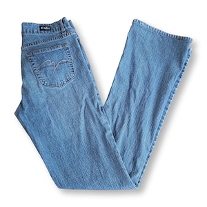 Peut inclure: Jean en denim bleu délavé moyen avec une coupe classique à cinq poches, une fermeture à bouton et fermeture éclair, et un emblème brodé de couleur claire sur la poche arrière. La ceinture comporte une petite étiquette noire.