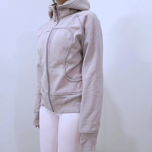 Peut inclure: Un sweat à capuche zippé violet clair avec capuche et poches. Le sweat à capuche a une fermeture éclair complète et un aspect doux et texturé. Le design comprend un détail de couture incurvée sur le devant.