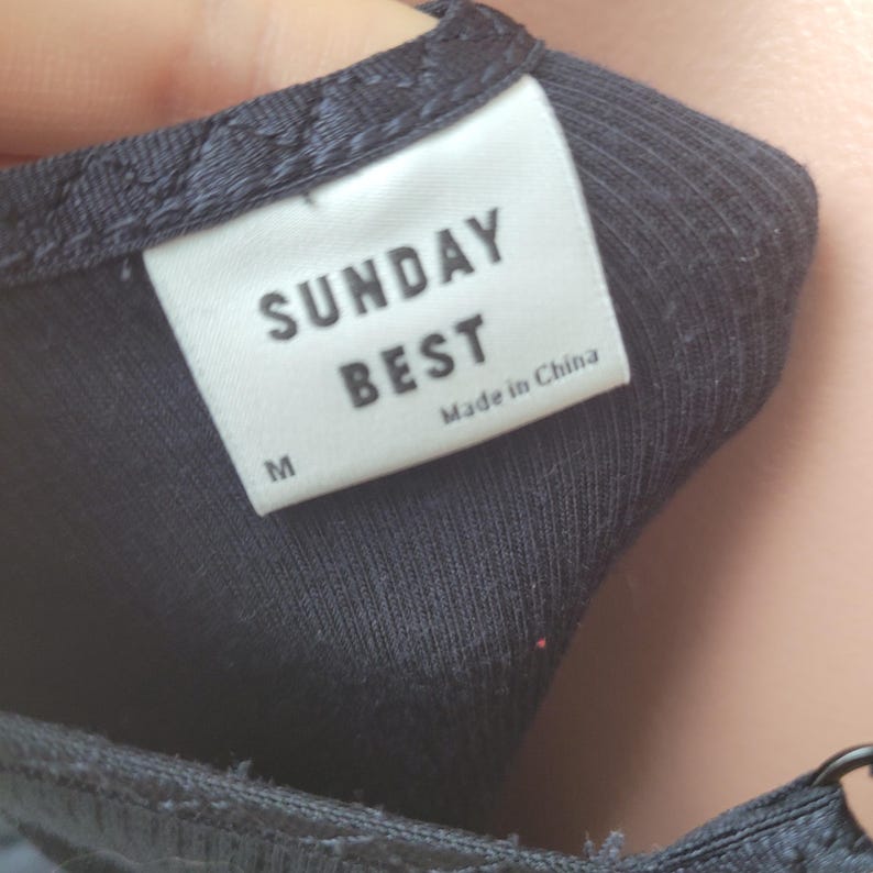 Peut inclure: Gros plan sur un haut c&ocirc;tel&eacute; bleu marine avec une &eacute;tiquette blanche. L'&eacute;tiquette indique "SUNDAY BEST" en gras, en noir, avec "Made in China" en dessous. La taille "M" est imprim&eacute;e sur l'&eacute;tiquette. Le haut est en tissu c&ocirc;tel&eacute; doux.