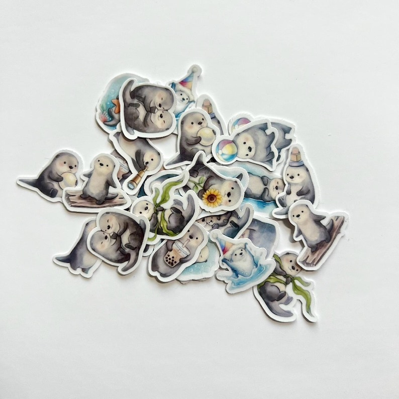 May include: A collection of die-cut stickers featuring watercolor illustrations of sea otters in various poses. The otters are depicted holding items like boba tea, sunflowers, telescopes, and beach balls, or wearing party hats and scarves.