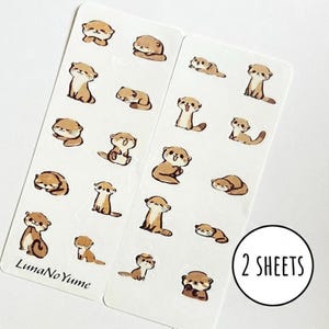 Könnte beinhalten: Zwei rechteckige Aufkleberbögen mit mehreren kleinen, braun-cremefarbenen Cartoon-Otter-Illustrationen in verschiedenen Posen. Der Text LunaNoYume ist unten links aufgedruckt und eine kreisförmige Grafik zeigt 2 SHEETS an.