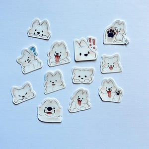 May include: A collection of white, cloud-shaped stickers featuring cartoon dogs with various expressions. Some stickers show the dogs with their tongues out, paw prints, or question marks. The stickers are on a light blue background.