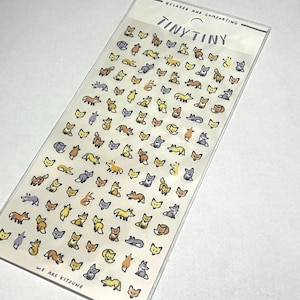 Puede incluir: Una hoja de pegatinas Tiny Tiny con dibujos de zorros en tonos marrón, amarillo y gris. Las pegatinas están sobre un fondo transparente con el texto "Relaxed and Comforting" y "We are Kitsune".