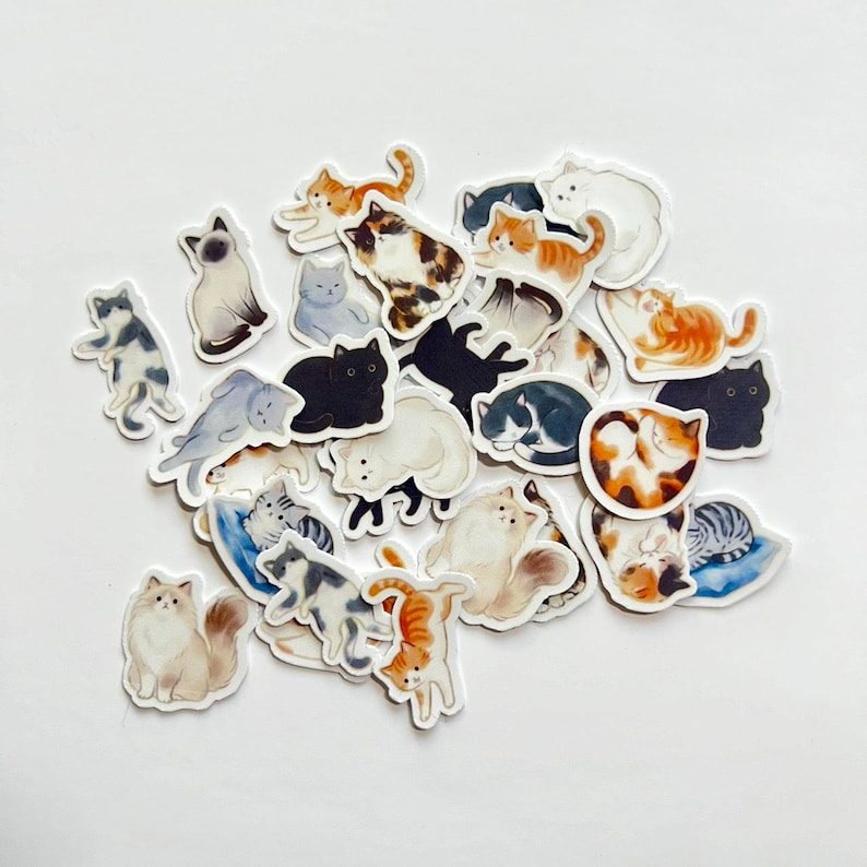 May include: A collection of die-cut stickers featuring various cat breeds and poses. The illustrations include orange tabbies, black cats, calico cats, and fluffy long-haired cats in sitting, sleeping, and stretching positions with white borders.