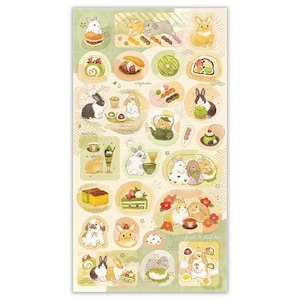 May include: A sticker sheet featuring various illustrations of rabbits with Japanese sweets and matcha. The designs include bunnies with mochi, tea, and desserts, in a soft, pastel color palette. The word "wagashi" is visible.