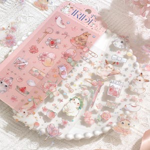 May include: A sheet of decorative stickers with a pink background and various illustrations. The stickers feature bunnies, flowers, peaches, and other cute designs. The word "IRIDE" is printed at the top. The stickers are on a white plate.