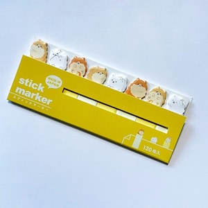 Può includere: Una confezione di stick marker con un design giallo e bianco. I marker presentano illustrazioni di cani dei cartoni animati in vari colori. La confezione riporta la scritta "stick marker" e "MADE IN JAPAN". La confezione contiene 120 marker.