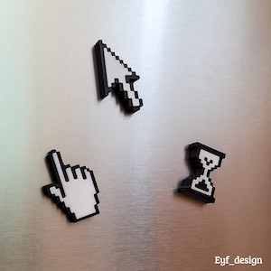 May include: Three pixelated computer cursor magnets in black and white. The set includes a mouse pointer, a hand pointer, and an hourglass icon. The magnets are displayed on a silver metallic surface.