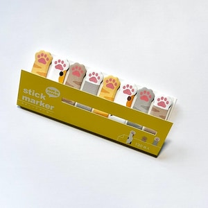 May include: A pack of cat paw-shaped sticky note markers. The markers are in various colours, including yellow, white, and grey, with pink paw pads. The package is yellow and has the words "stick marker" printed on it.