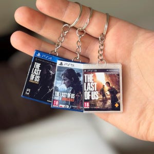 Puede incluir: Tres llaveros con estuches de juego en miniatura de "The Last of Us" para PS4, PS5 y PS3. Cada estuche muestra una carátula diferente y el título del juego. Los llaveros están sujetos a anillos de metal plateado.