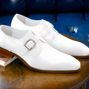 Handmade white leather monk strap shoes for men with silver buckle, sleek formal dress shoes isolated on white background