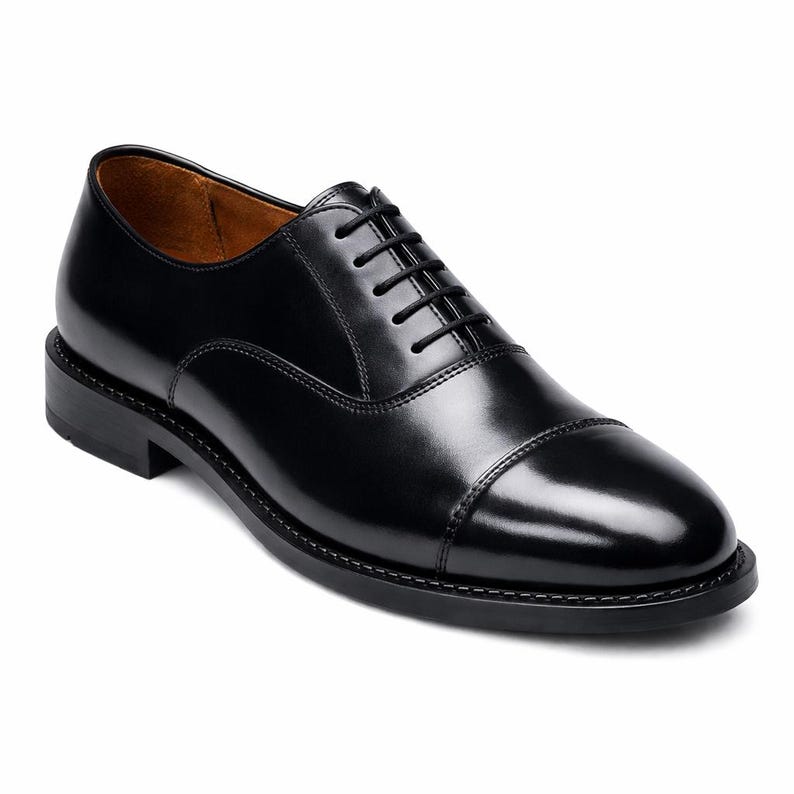 Peut inclure: Une chaussure oxford en cuir noir poli avec un bout droit classique, un petit talon empil&eacute; et des lacets noirs fins. La doublure int&eacute;rieure est de couleur beige chaud, et la chaussure pr&eacute;sente une finition ext&eacute;rieure lisse et brillante.