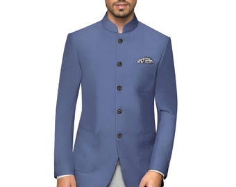 May include: A light blue suit jacket with a mandarin collar, paired with light gray trousers. The jacket features a pocket square and a three-button closure. The outfit is completed with dark loafers.
