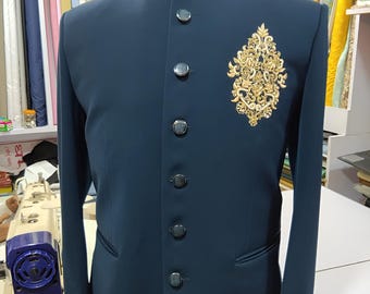May include: A dark teal suit jacket with a mandarin collar and six dark buttons. The jacket features an ornate gold embroidered design on the chest. The mannequin is size 40. The jacket is displayed in a tailor shop.
