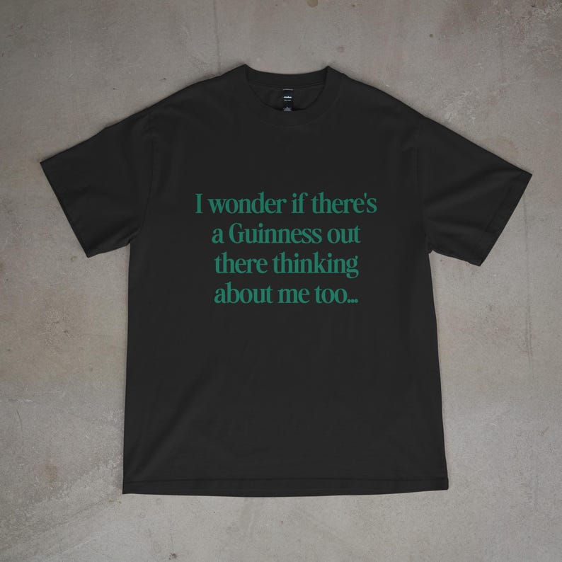 May include: Black t-shirt with the teal text: "I wonder if there's a Guinness out there thinking about me too...". The shirt is made of a soft material and has a crew neck.