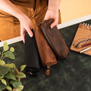 May include: A set of three ceramic mugs with a speckled, matte finish. The mugs are in shades of cream, light gray, and dark gray. Each mug has a simple, minimalist design, perfect for coffee or tea.