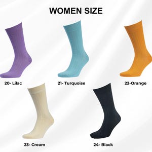 K&ouml;nnte beinhalten: F&uuml;nf Paar Damensocken in verschiedenen Farben: Flieder, T&uuml;rkis, Orange, Creme und Schwarz. Jede Socke hat eine gerippte Textur. Der Text "WOMEN SIZE" steht oben, mit Farbnamen und Nummern unter jeder Socke.