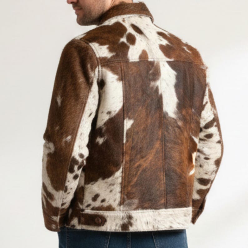 Puede incluir: Chaqueta de piel de vaca marr&oacute;n y blanca con cierre de bot&oacute;n. La chaqueta tiene un cuello cl&aacute;sico y un bolsillo en el pecho. La chaqueta est&aacute; hecha de un material suave y texturizado.