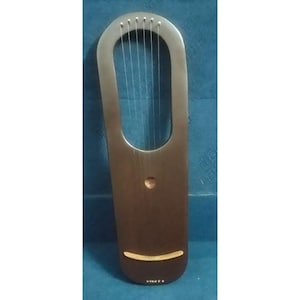 May include: A wooden lyre with a dark brown body and a silver-coloured top section. Six strings are strung across the opening. A small, round sound hole is visible. The lyre is a stringed musical instrument.