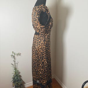 Puede incluir: Vestido largo con estampado de leopardo y ribete de encaje negro en el bajo. El vestido se exhibe en un maniqu&iacute; negro. El vestido presenta un dise&ntilde;o recortado en la cintura y una parte superior sin mangas.