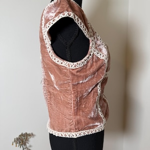 Puede incluir: Top de terciopelo rosa empolvado con ribete de ganchillo blanco. El top sin mangas se muestra en un maniqu&iacute; negro. El ribete de ganchillo perfila el escote, las sisas y el dobladillo inferior del top. La tela de terciopelo tiene un aspecto suave y texturizado.