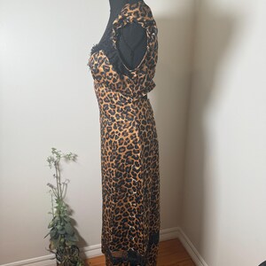 Puede incluir: Vestido con estampado de leopardo con ribete de encaje negro y mangas con volantes. El vestido se exhibe en un maniqu&iacute; negro. El vestido tiene un escote redondo y una silueta ajustada. El vestido est&aacute; hecho de una tela ligera.