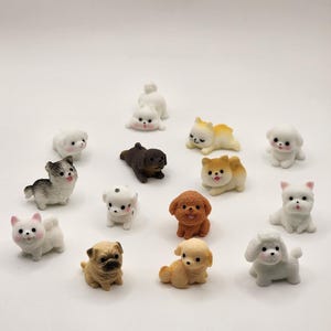 May include: A collection of small, decorative dog figurines in various breeds and poses. The figurines are in shades of white, brown, and tan, with some featuring black and gray markings. Each dog has a cute, cartoonish design.