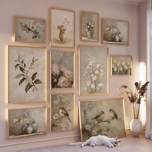 May include: A collection of framed botanical and animal art prints in a variety of sizes. The prints feature soft, muted colors and depict flowers, birds, and a mouse. The frames are gold-toned, and the overall aesthetic is vintage and elegant.