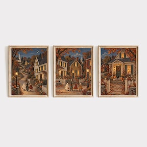 Könnte beinhalten: Ein Set aus drei gerahmten Kunstdrucken, die eine Nachbarschaftsszene im Herbst in der Dämmerung zeigen. Die Bilder zeigen Häuser, Bäume mit orangefarbenem Laub, Straßenlaternen und kostümierte Kinder, die auf Wegen spazieren gehen.