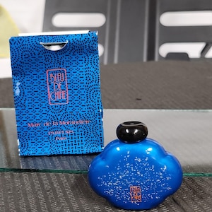 Pu&ograve; includere: Un flacone di profumo blu con tappo nero e scatola abbinata. Il flacone ha la forma di una nuvola con macchie bianche. La scatola e il flacone riportano la scritta "BLEU DE CHINE" e altro testo.