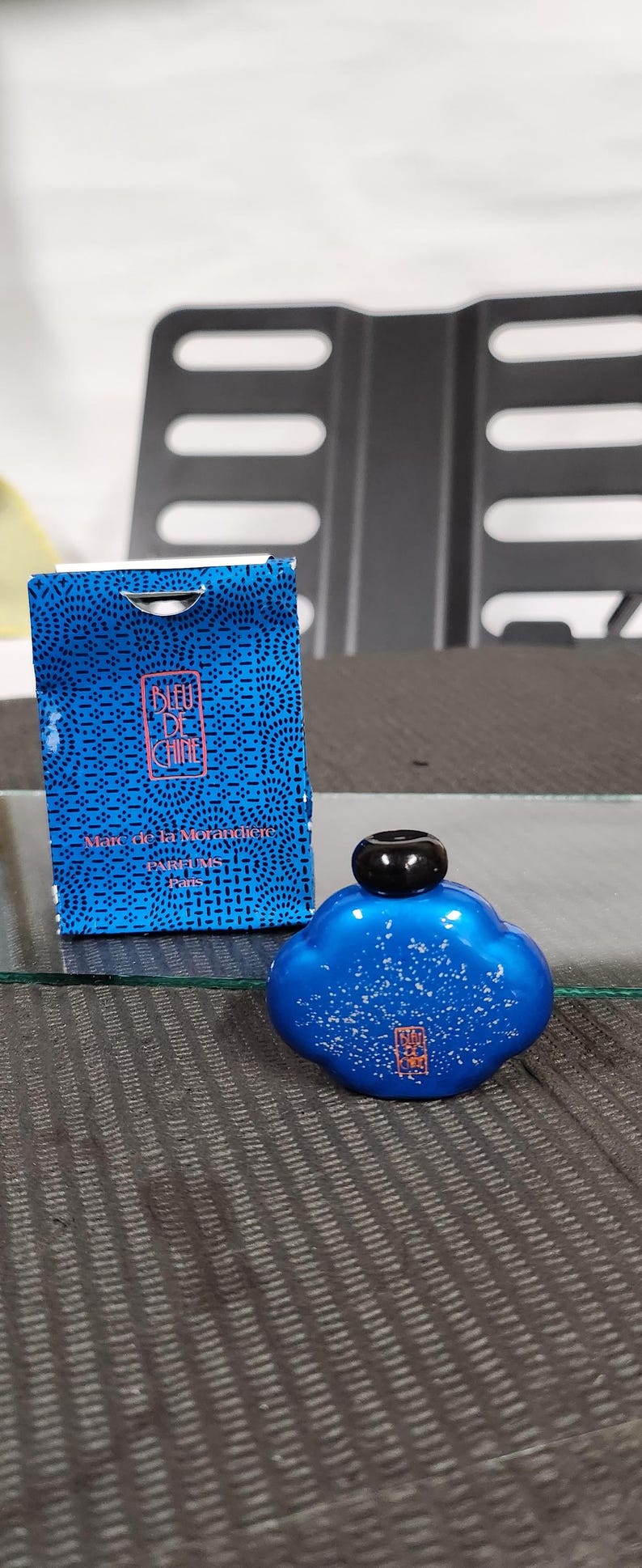 Pu&ograve; includere: Un flacone di profumo blu con tappo nero e scatola abbinata. Il flacone ha la forma di una nuvola con macchie bianche. La scatola e il flacone riportano la scritta "BLEU DE CHINE" e altro testo.