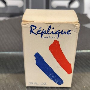 May include: A vintage perfume box labeled "Réplique parfum" with blue and red diagonal stripes. The box is off-white and has a .29 fl. oz. measurement on the bottom.