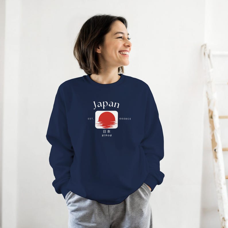 May include: Navy blue sweatshirt with a white and red graphic featuring the word "Japan" and a rising sun design. The sweatshirt also includes Japanese characters and the text "EST. 660BCE".