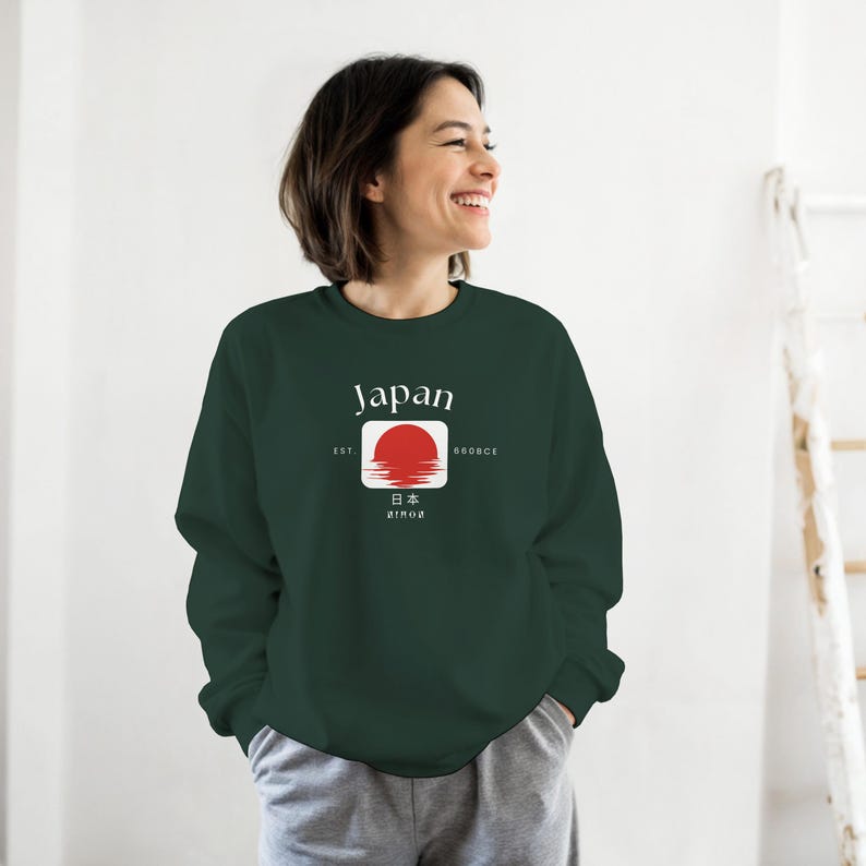 May include: A dark green sweatshirt with the word "Japan" in white above a red sun design. The design includes Japanese characters and the words "EST" and "800BCE". The sweatshirt is a comfortable, casual style.